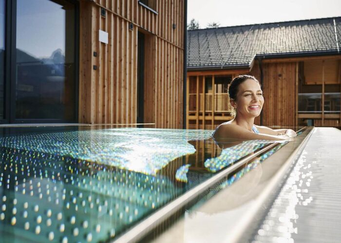 A woman relaxes in a modern pool, enjoying the serene ambiance of Schladming's beautiful architecture.