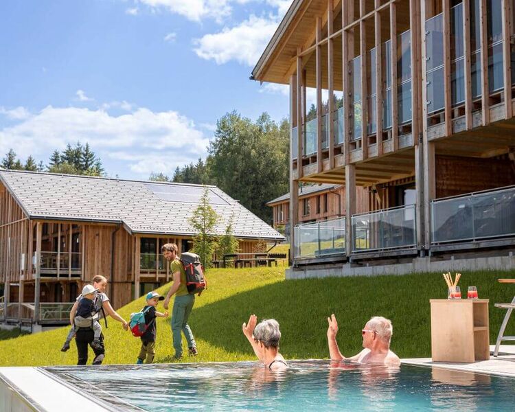 Grandparents wave to the wandering young family from the private pool of their holiday home.