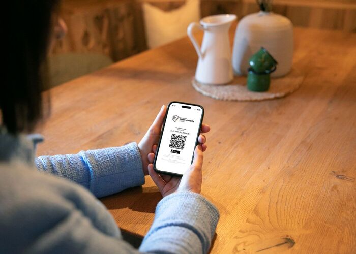 Frau hält ihr Handy mit dem Guest Mobility Ticket in der Hand.