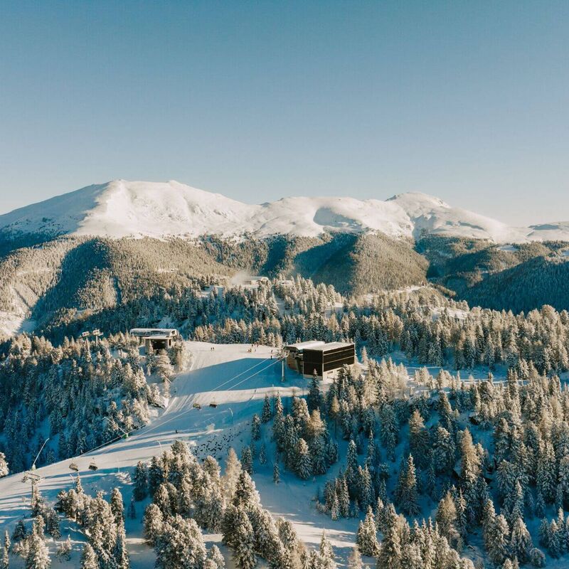 Skipiste schlängelt sich durch tiefverschneite Wälder im schneesicheren Skigebiet Turracher Höhe