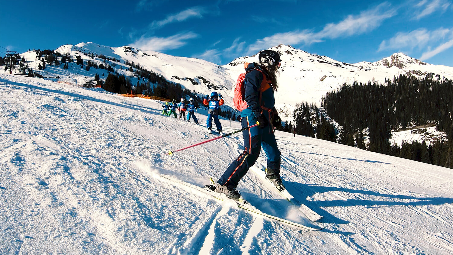 Ski instructor practicing plough turns with a group of children on the slopes