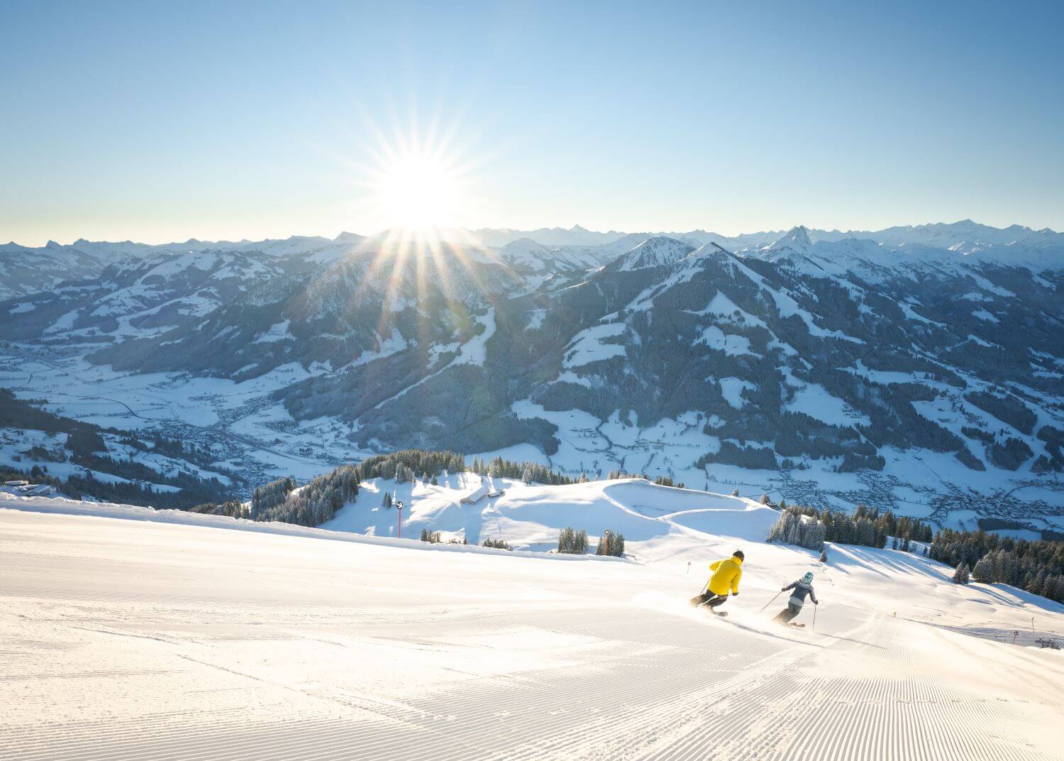 Zwei Skifahrer auf der frisch präparierten Piste mit Panoramablick