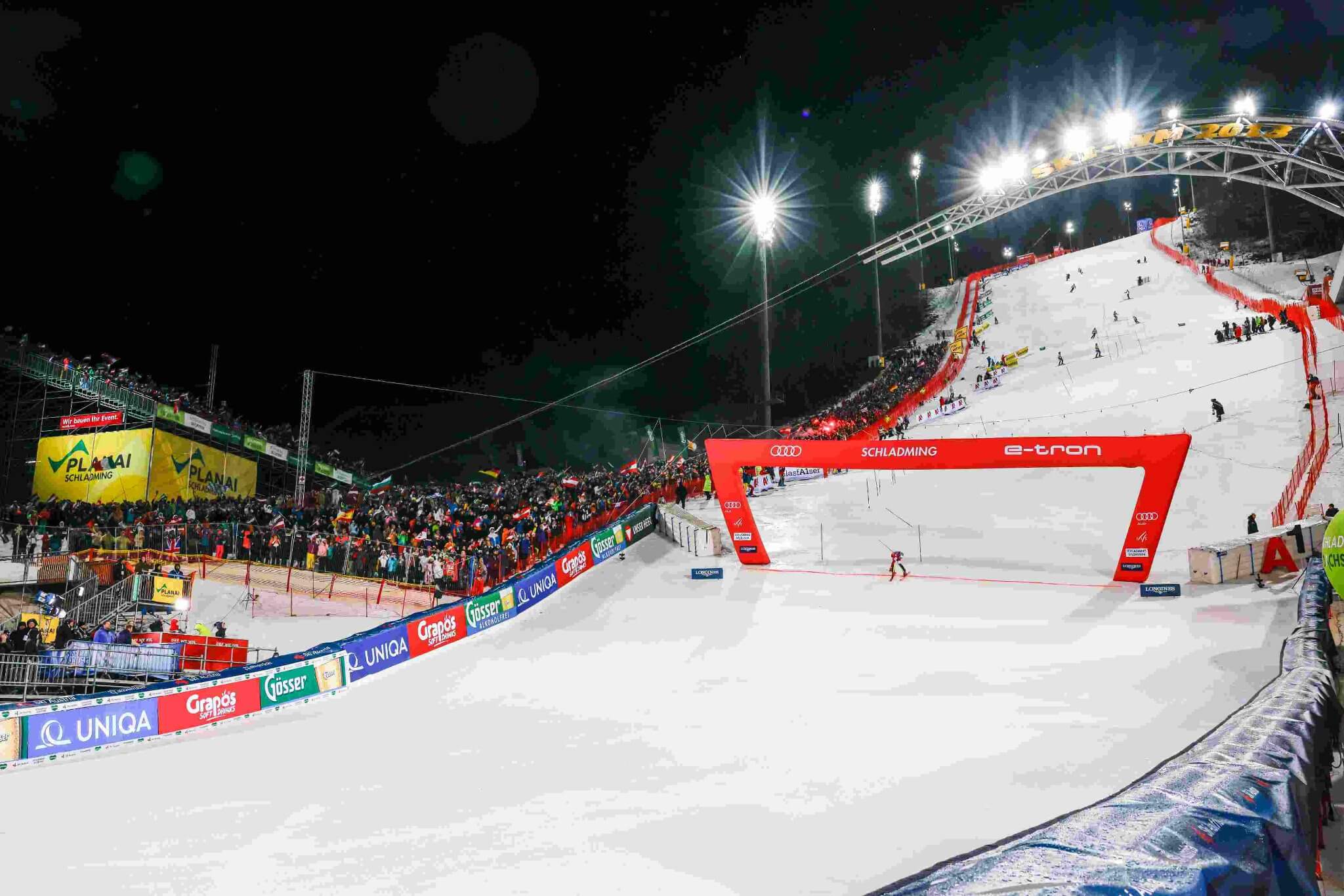 Nacht-Skiwettbewerb in Schladming mit zahlreichen Zuschauern und einer beleuchteten Piste im Hintergrund.