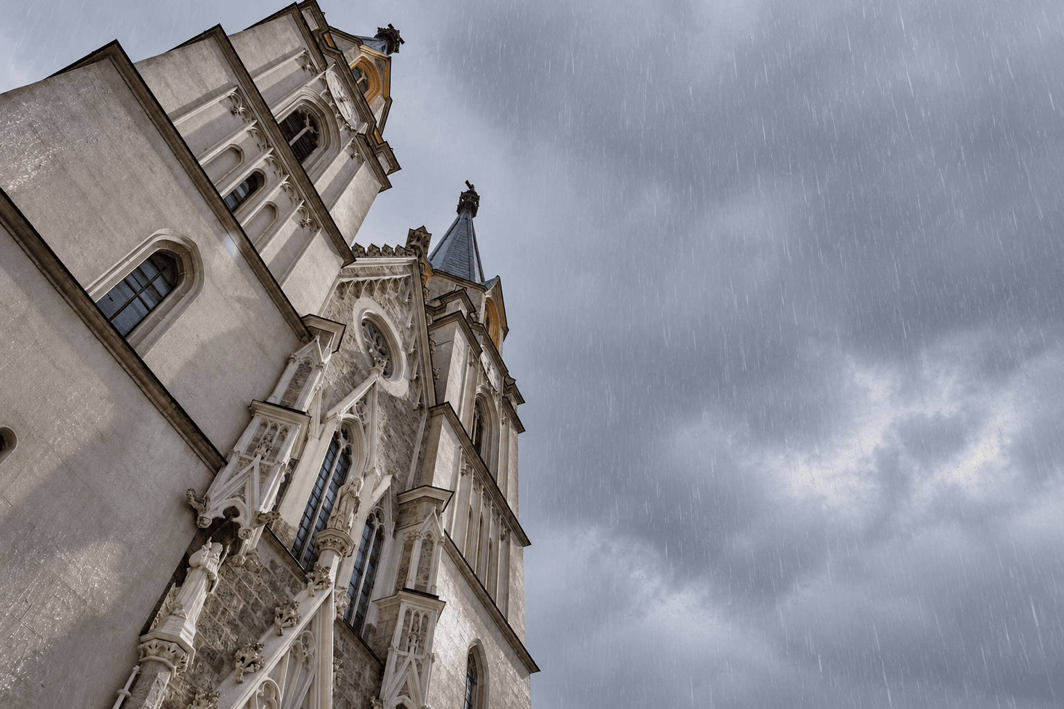 Towers of Admont Abbey Church against dark rain clouds