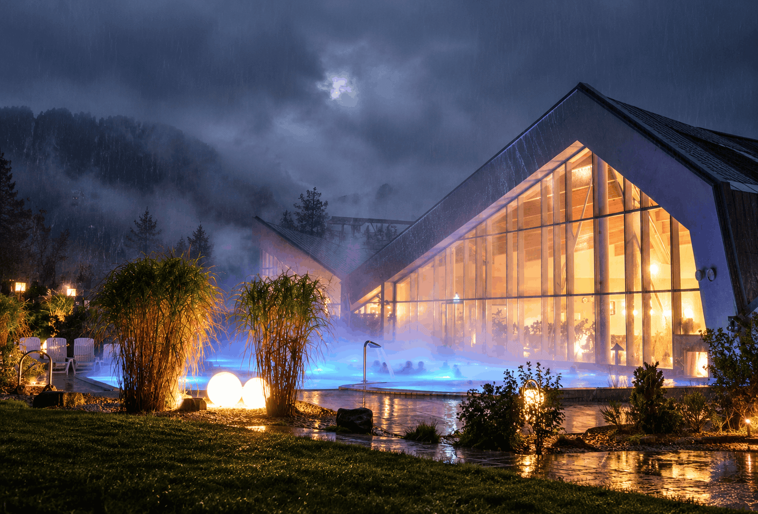 Illuminated building of Erlebnis-Therme Amadé with a steaming outdoor pool in the evening