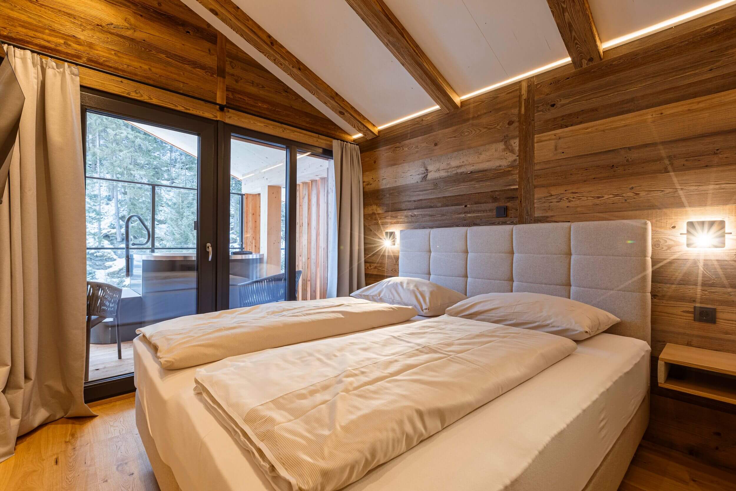 Schlafzimmer im Penthouse der Saalbach Suites mit komfortablem Bett und modernem alpinen Interieur, hell und einladend.