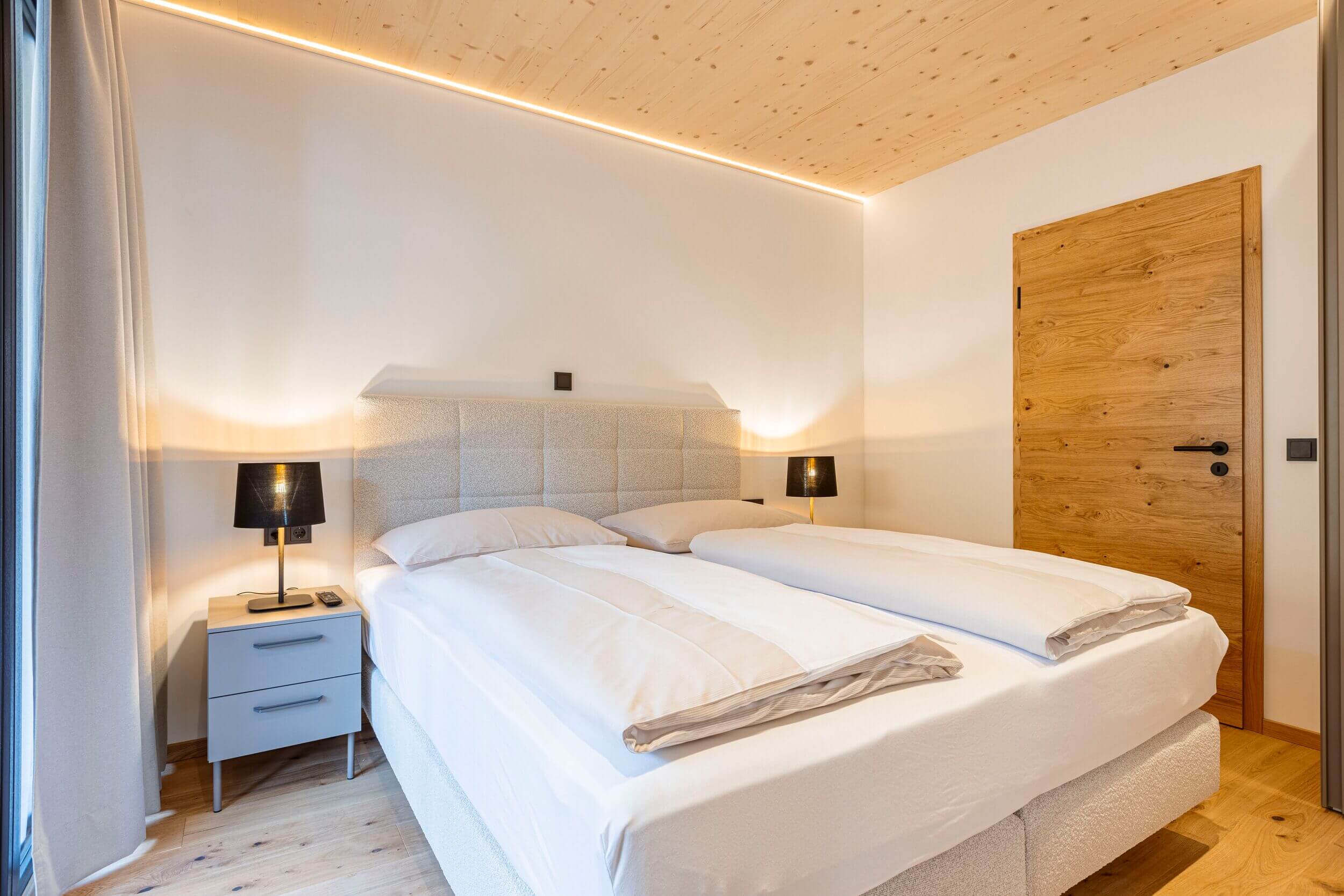 Modernes Schlafzimmer in den Saalbach Suites mit gemütlichem Bett und stilvoller Einrichtung für erholsame Nächte.