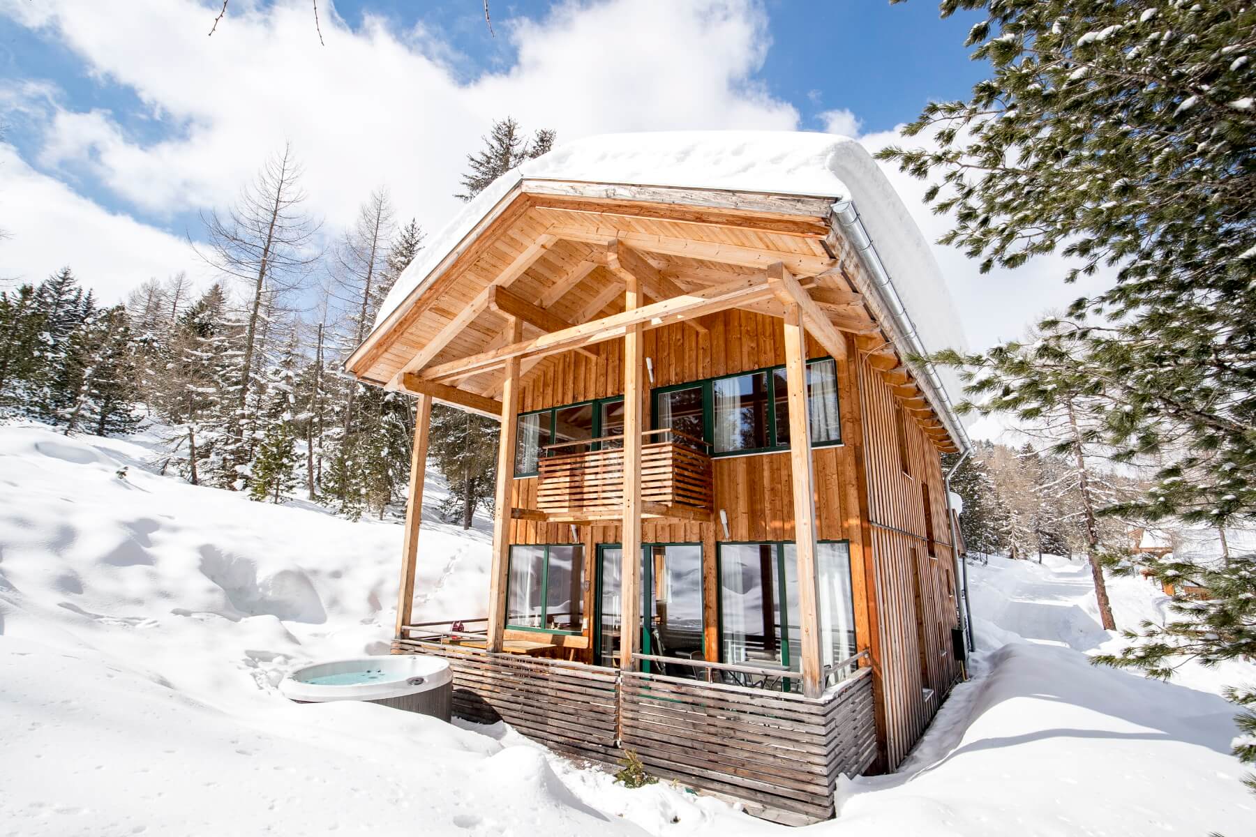 Ferienhaus in Schnee bedeckter Waldlandschaft und Hot Tub