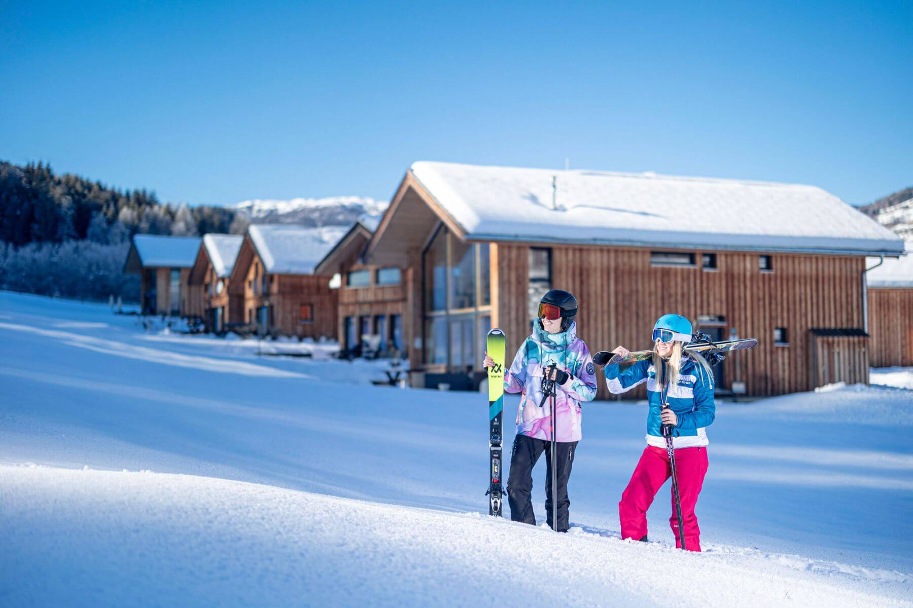 Skiers stand in the deep snow in front of the holiday homes