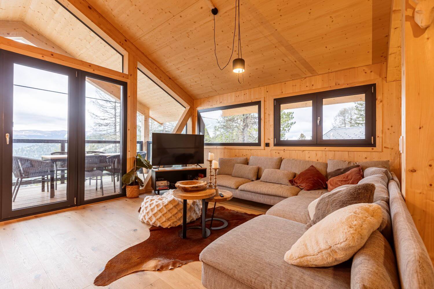 Gemütlicher Wohnbereich in einem Ferienhaus mit Ausblick auf den Zirbenwald